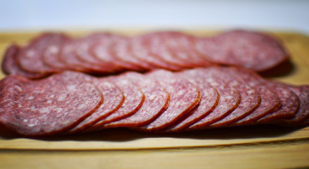 Slices of salami on a cutting board on a wooden table close up