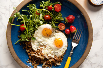 Two sunny side up eggs on a plate with salad