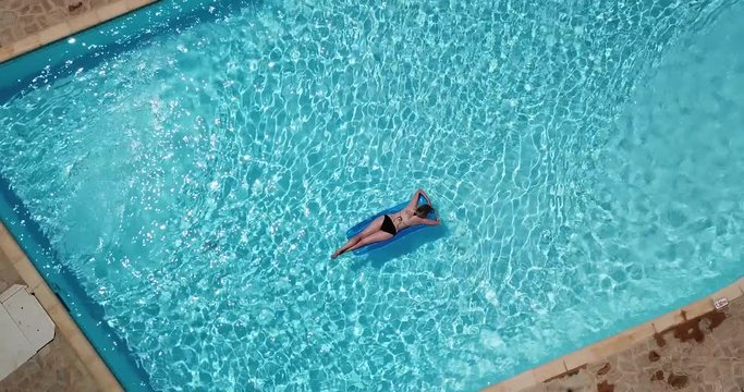 frau im bikini treibt auf luftmatratze in pool
