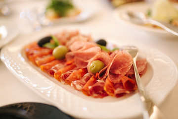 Appetizer in restaurant. Banquet concept. cold meat plate with prosciutto, slices ham, salami, decorated with olive