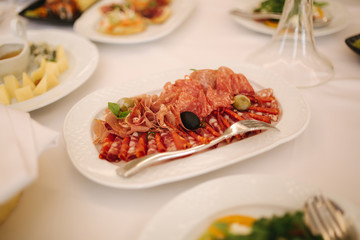 Appetizer in restaurant. Banquet concept. cold meat plate with prosciutto, slices ham, salami, decorated with olive