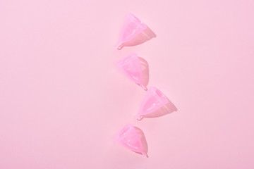 top view of pink plastic menstrual cups on pink background