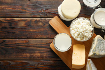 Flat lay. Fresh dairy products and cutting board on wooden background