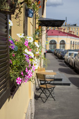 Flowers on window. Two chairs and a table on the street near the house