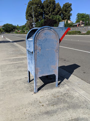 Old Blue Mailbox on Sidewalk Next To a Street