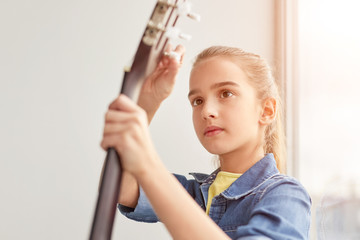 Focused girl tuning guitar