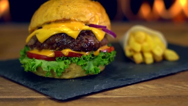 Saftiger Burger mit Pommes vor Feuer