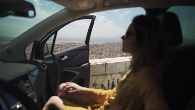 Woman sitting in car on top of mountain with view of town Trapani in Sicily