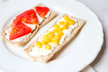 Homemade Crispbread toast with Cottage Cheese and green olives,slices of cabbage,tomatoes,corn,green pepper on cutting board on white concrete background.Healthy food concept,Top view.Flat Lay