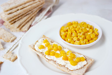 Homemade Crispbread toast with Cottage Cheese and green olives,slices of cabbage,tomatoes,corn,green pepper on cutting board on white concrete background.Healthy food concept,Top view.Flat Lay