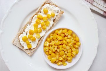 Homemade Crispbread toast with Cottage Cheese and green olives,slices of cabbage,tomatoes,corn,green pepper on cutting board on white concrete background.Healthy food concept,Top view.Flat Lay