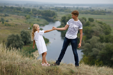 Fototapeta premium Brother and sister stays on the hill above the river
