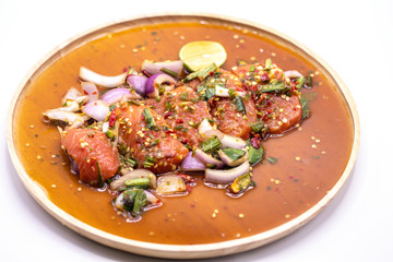 Thai spicy salmon salad in wooden plate isolate on white background.