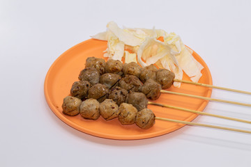 Grilled meatballs on a wooden stick with in orange plate isolate on white background.