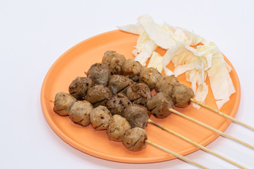 Grilled meatballs on a wooden stick with in orange plate isolate on white background.