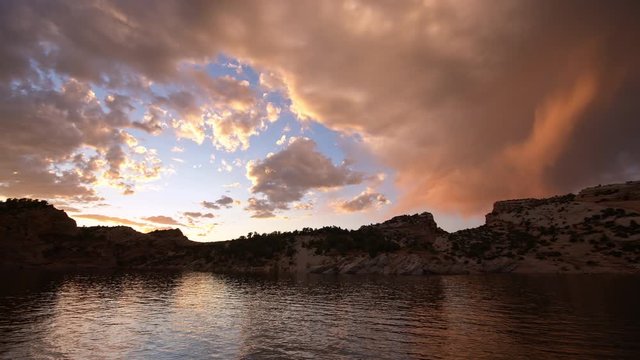 Clouds lit up at sunset over lake in the Utah desert panning in slow motion.