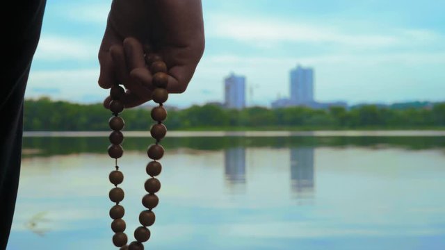 Close-up, Man Reads Mantra Holding Rosary in Hand on River Bank
