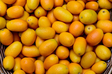 Bunch of fresh ripe organic kumquats in display for sale at a street food market, soft focus