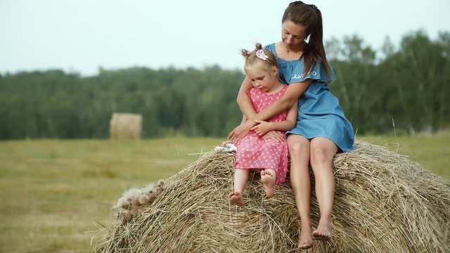Mother with little daugter on haystack