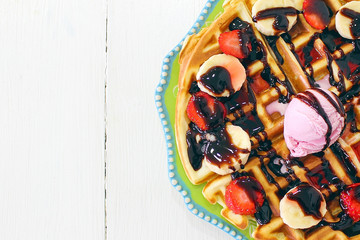 Young girl sitting caffe eating breakfast waffle with chocolate sauce,banana slices and strawberries on green ceramic plate and photographed her breakfast,space for text