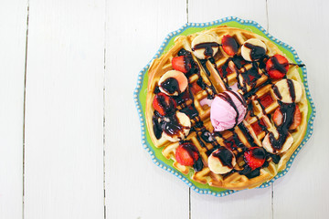 Young girl sitting caffe eating breakfast waffle with chocolate sauce,banana slices and strawberries on green ceramic plate and photographed her breakfast,space for text