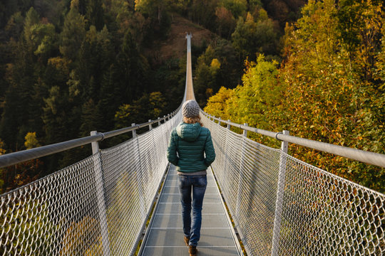 Fototapeta Woman walking along a suspension bridge