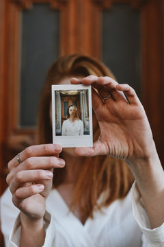 Woman holding instant photo in front of her face