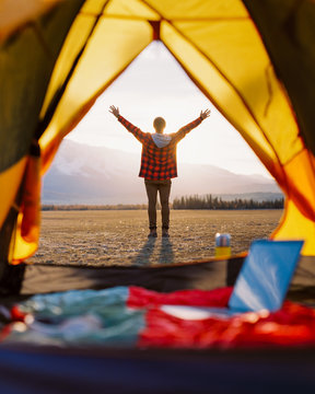 Vew through the tent. Guy traveler enjoy the rising sun and beautiful nature