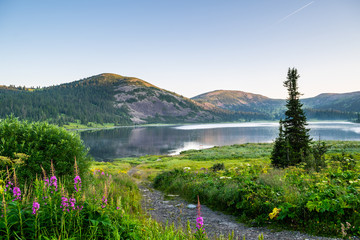 View on mountain lake with hills and green forest during sunrise. Ergaki national park, Siberia, Russia