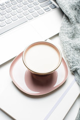 Beautiful enameled pink cup of coffee with blanket and laptop
