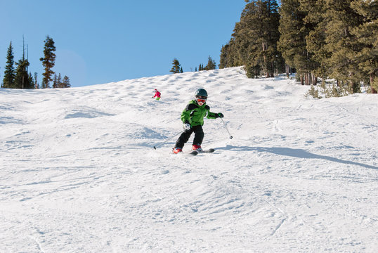 Child skiing through moguls on a sunny day in winter