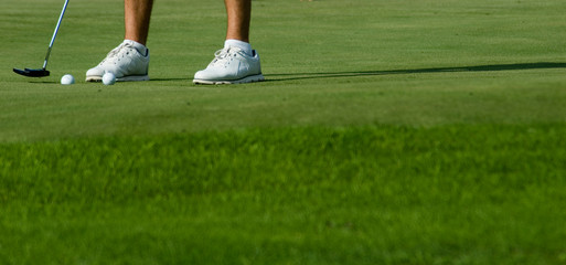 man doing exercise on the green of a golf course to pull the ball into the hole, grass, sunset,...