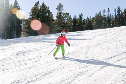 Child in bright ski clothes on a groomed ski run