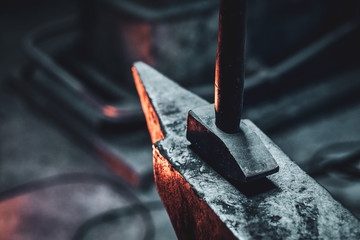 Close up photo shoot of hammer and anvil at dark smith workshop. - obrazy, fototapety, plakaty
