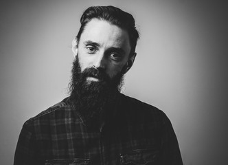 Black and white photo of pensive man with beard on the light background.