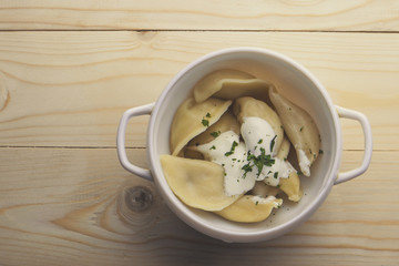Bowl with tasty dumplings on wooden table