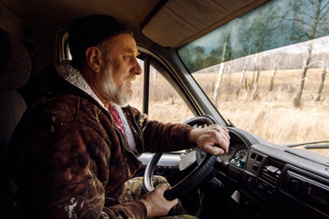 Elderly male steering car in countryside