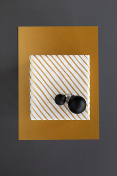 Diagonally striped gold and white christmas present and black ornaments