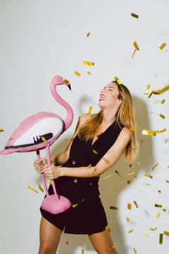 Funny woman holding a flamingo toy in a New Year party celebration.