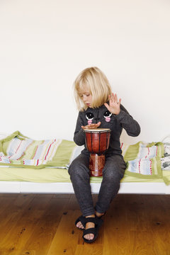 Girl playing bongo on bed