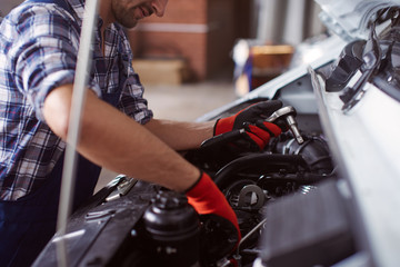 Close up of a man fixing broken car engine.