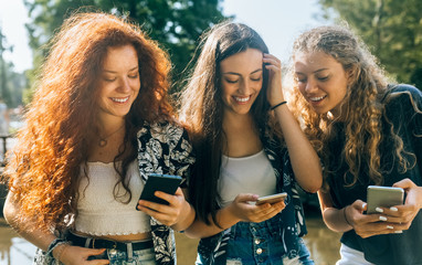 Three young friends using their smartphone