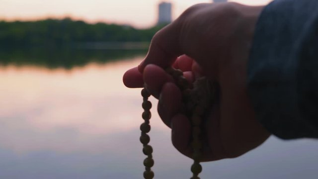Close-up, Men Hand Holds Little Rosary, Evening Prayer on the River Bank