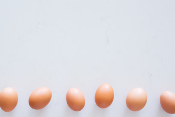 row of brown eggs on white background