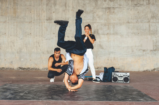 Young male performing a dance pose in the park surrounded by mixed race group of friends
