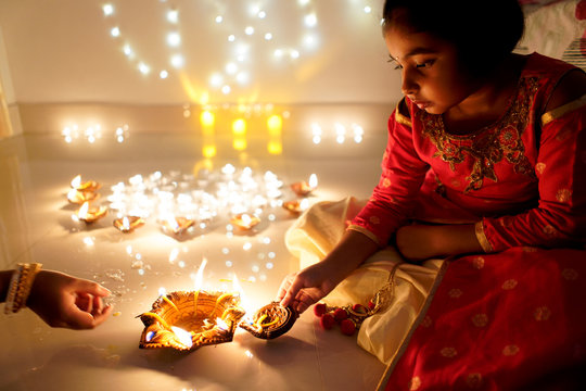 Little girl lighting earthen oil lamps on Diwali