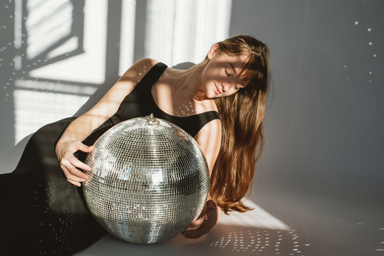 Young woman lying close to mirror-ball