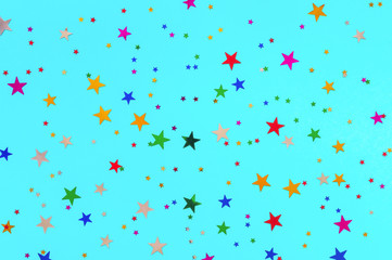 Multicolored stars sprinkles on turquoise backdrop. Festive holiday background. for your projects. Celebration concept. Christmas pattern. Top view, flat lay