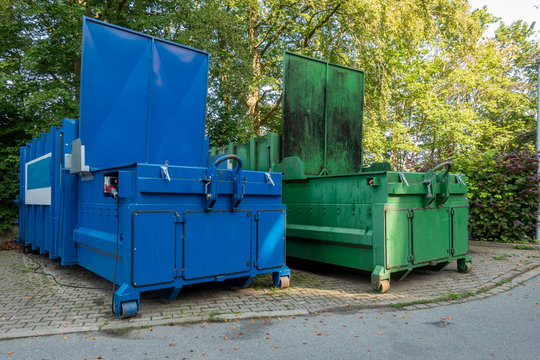 two garbage compactors Standing next to each other on the premises of a hospital