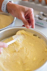 woman spreading batter with spatula in cake pan